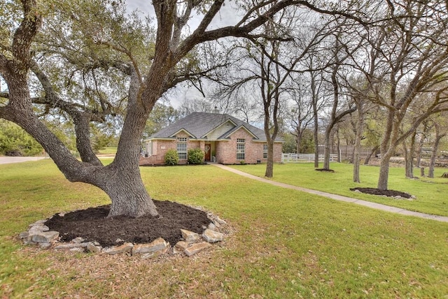 view of front facade featuring a front lawn, fence, and brick siding