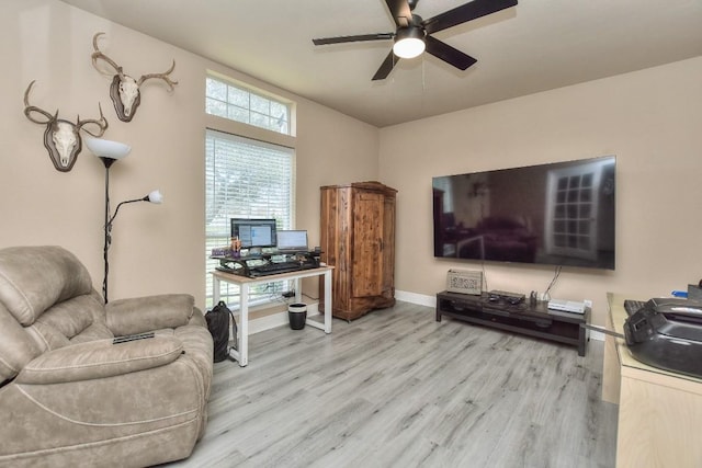 living room featuring baseboards, light wood-style flooring, and a ceiling fan