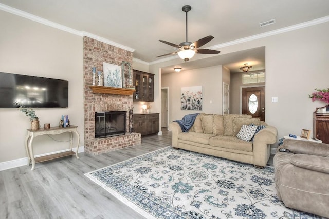 living room featuring visible vents, wood finished floors, a fireplace, crown molding, and baseboards