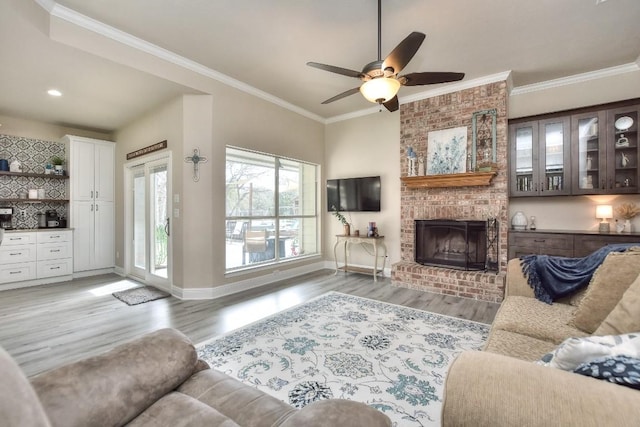 living room with baseboards, light wood-style floors, ornamental molding, and a fireplace