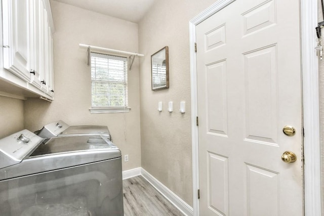 laundry room with light wood-type flooring, baseboards, cabinet space, and independent washer and dryer