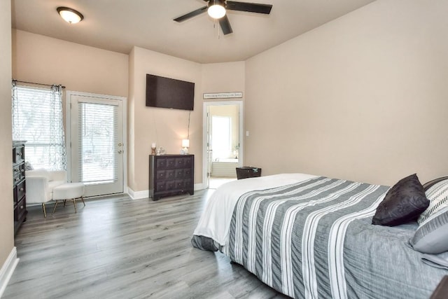 bedroom featuring access to outside, wood finished floors, connected bathroom, baseboards, and ceiling fan