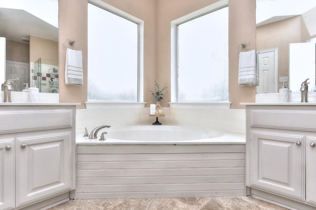 bathroom featuring a sink, walk in shower, a garden tub, and two vanities