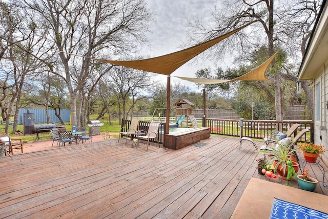 deck with a playground and a fenced backyard