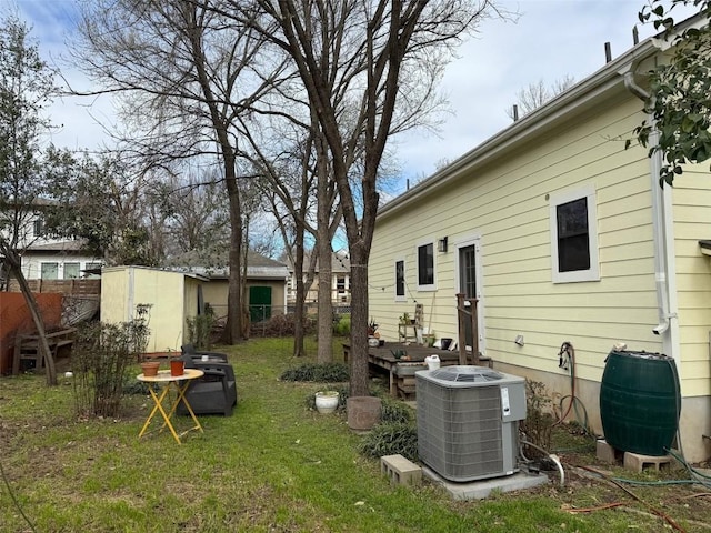 view of yard featuring an outdoor structure, a storage unit, fence, and central AC