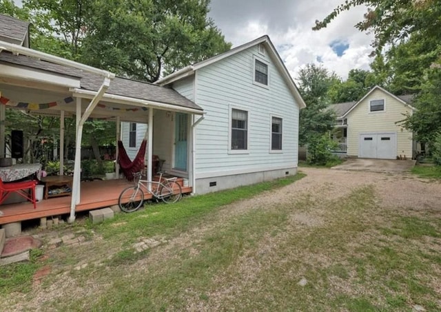 rear view of house with an outdoor structure, a garage, dirt driveway, crawl space, and a lawn