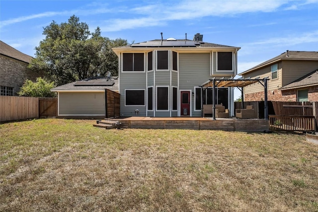 back of house featuring solar panels, a fenced backyard, a pergola, a deck, and a lawn