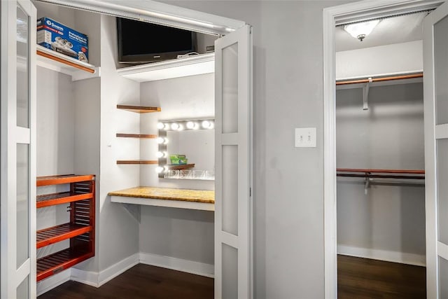 walk in closet featuring built in desk and dark wood-style flooring