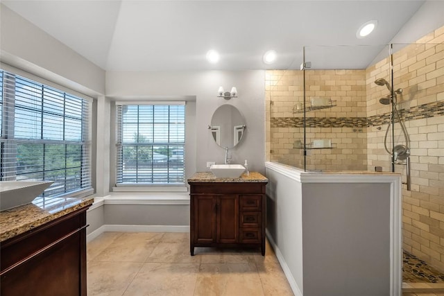 bathroom featuring vanity, vaulted ceiling, baseboards, and walk in shower