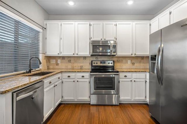 kitchen with dark wood finished floors, decorative backsplash, stainless steel appliances, white cabinetry, and a sink