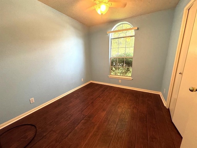 unfurnished room featuring ceiling fan, baseboards, and dark wood-style floors