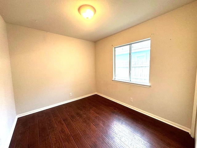 unfurnished room with dark wood-type flooring and baseboards