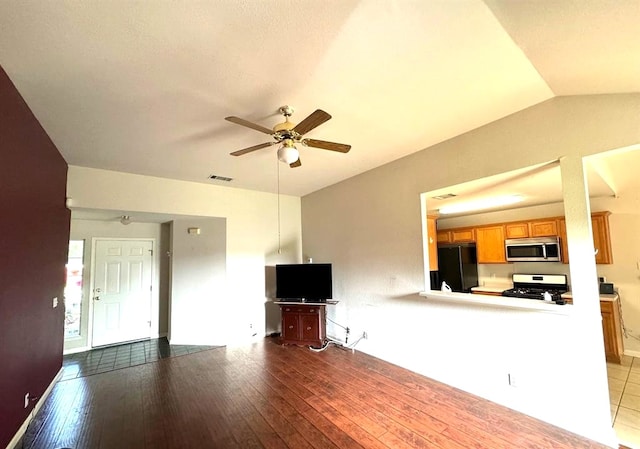 unfurnished living room with vaulted ceiling, visible vents, ceiling fan, and hardwood / wood-style floors