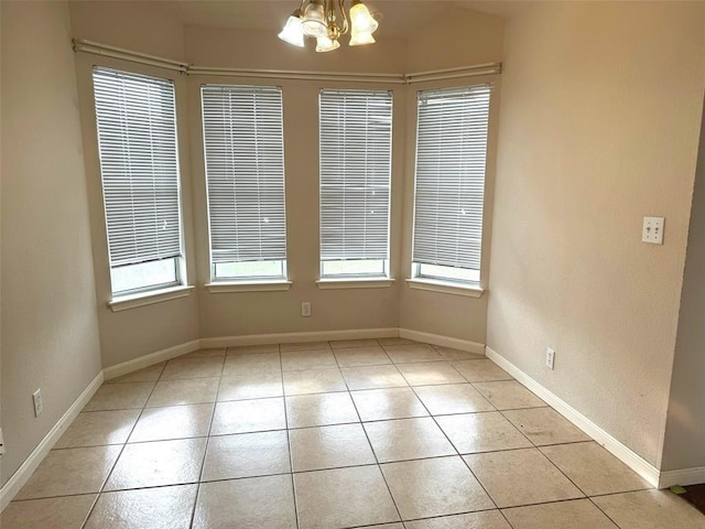 unfurnished dining area with light tile patterned floors, a notable chandelier, and baseboards