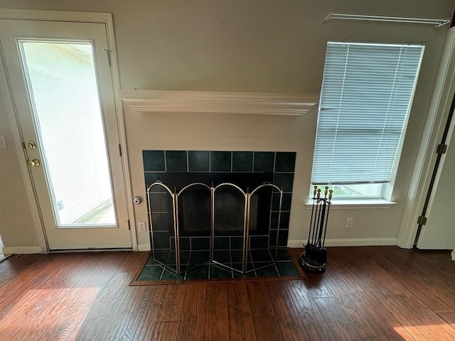 details with baseboards, wood finished floors, and a tiled fireplace