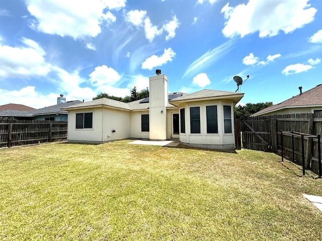 rear view of house featuring a patio, roof mounted solar panels, a lawn, and a fenced backyard