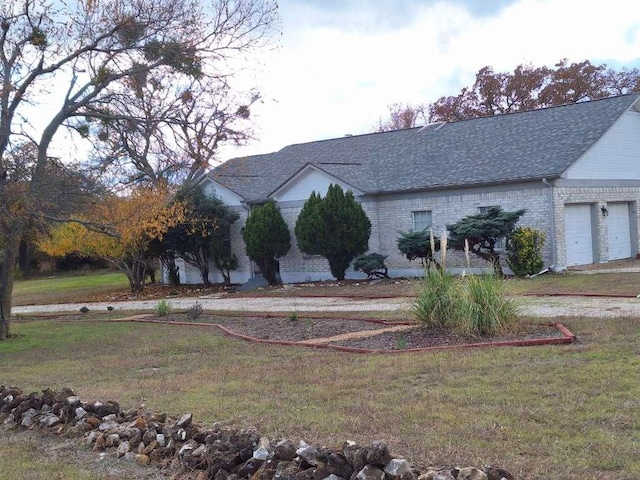 view of side of property featuring brick siding, a shingled roof, and a yard