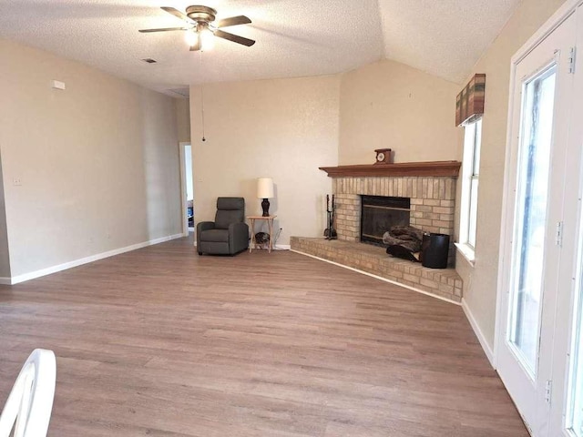 sitting room featuring a fireplace, a textured ceiling, lofted ceiling, and wood finished floors