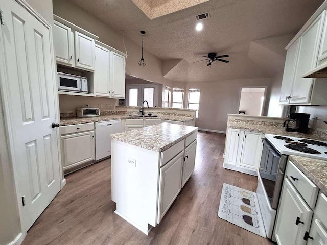 kitchen with visible vents, white appliances, a peninsula, and a sink