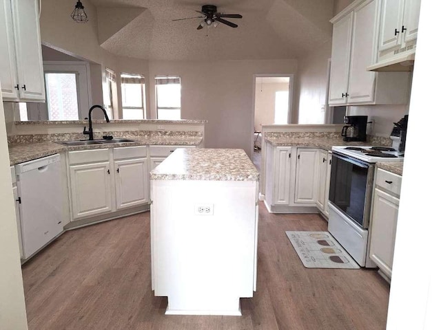 kitchen with a center island, under cabinet range hood, a peninsula, white appliances, and a sink