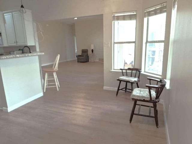 kitchen featuring baseboards, white cabinetry, light countertops, and light wood-style floors