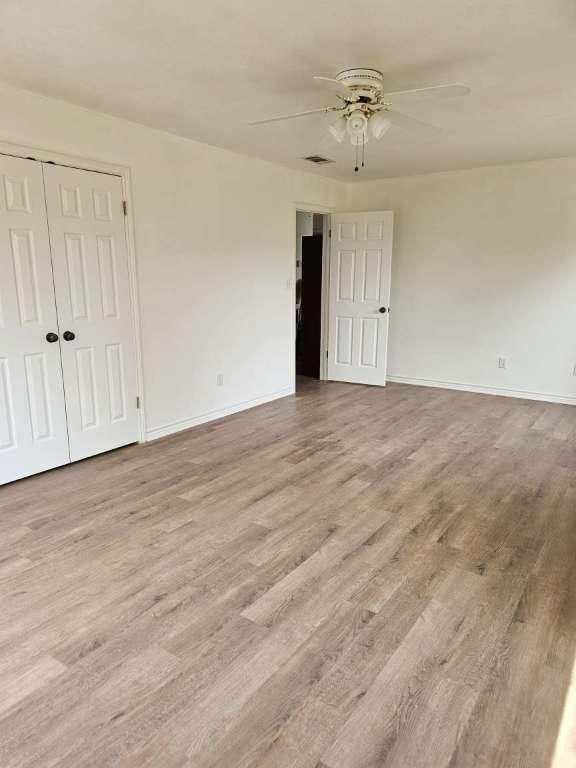 empty room with a ceiling fan, wood finished floors, and baseboards