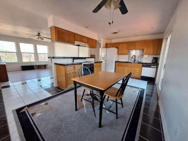 dining area featuring visible vents, baseboards, ceiling fan, and dark tile patterned flooring