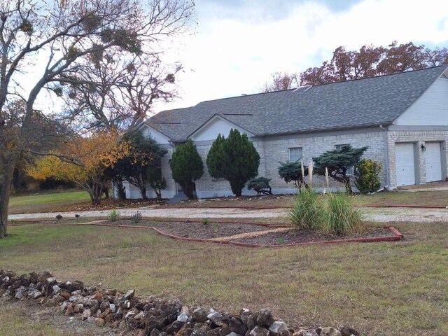 107 Patricia Rd, Georgetown, TX 78628 - view of front of home featuring a shingled roof, a front lawn, brick siding, and a garage