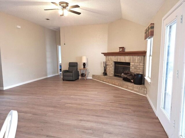 107 Patricia Rd, Georgetown, TX 78628 - living room with vaulted ceiling, a textured ceiling, ceiling fan, wood finished floors, and a brick fireplace