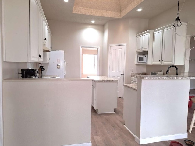 107 Patricia Rd, Georgetown, TX 78628 - kitchen with white appliances, a peninsula, recessed lighting, light wood-style floors, and a kitchen island