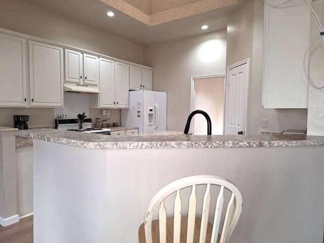 107 Patricia Rd, Georgetown, TX 78628 - kitchen with white appliances, under cabinet range hood, white cabinets, recessed lighting, and light countertops