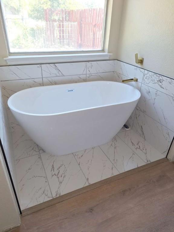 107 Patricia Rd, Georgetown, TX 78628 - bathroom featuring tile walls, a soaking tub, and wainscoting