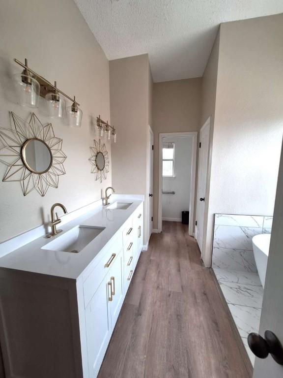 107 Patricia Rd, Georgetown, TX 78628 - full bath with a freestanding tub, a textured ceiling, double vanity, and wood finished floors