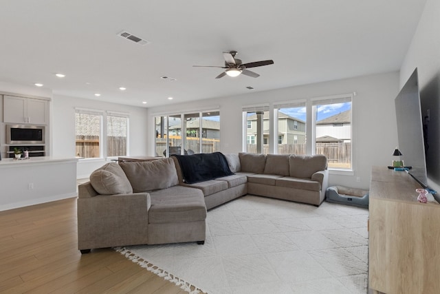 living area featuring visible vents, light wood-type flooring, a ceiling fan, recessed lighting, and baseboards