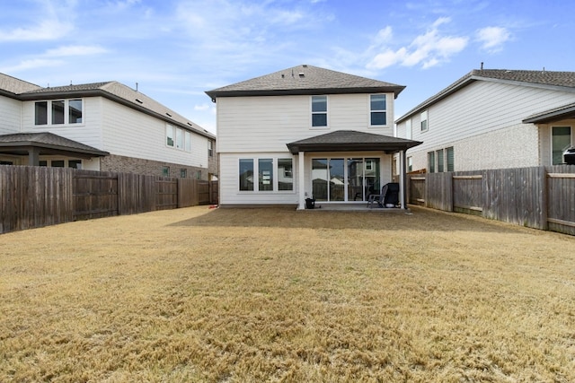 back of house featuring a yard, roof with shingles, a fenced backyard, and a patio area