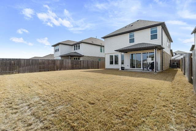 back of house featuring a patio area, a lawn, a fenced backyard, and a shingled roof