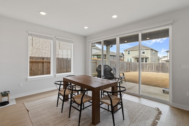 dining space with light wood-style flooring, baseboards, and a wealth of natural light