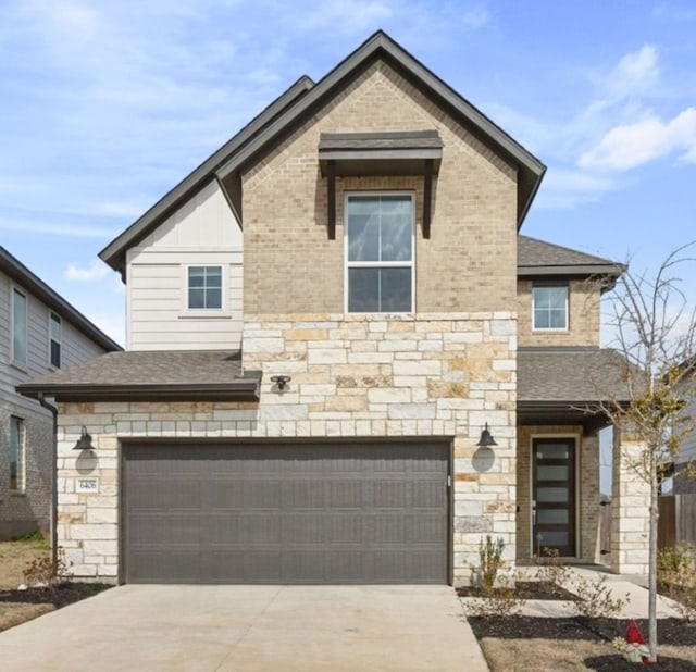 traditional-style house with stone siding, board and batten siding, concrete driveway, a shingled roof, and a garage