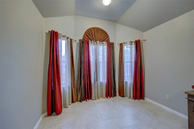 empty room with baseboards and vaulted ceiling