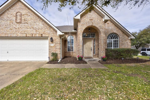 view of front of house featuring a front lawn, an attached garage, brick siding, and driveway