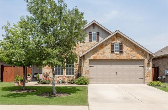 traditional home with fence, driveway, a front lawn, stone siding, and a garage