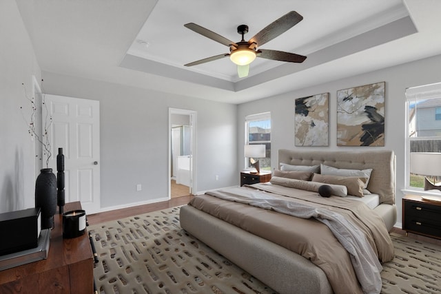 bedroom featuring multiple windows, a raised ceiling, and baseboards