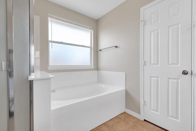 bathroom with baseboards, a garden tub, and tile patterned flooring