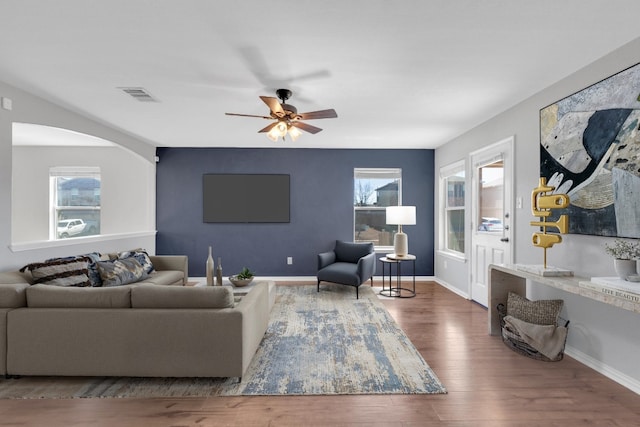 living area with visible vents, baseboards, wood finished floors, and a ceiling fan