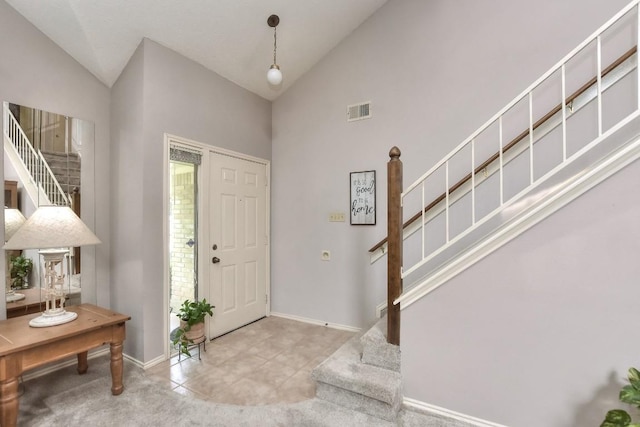 foyer entrance featuring stairs, baseboards, visible vents, and high vaulted ceiling