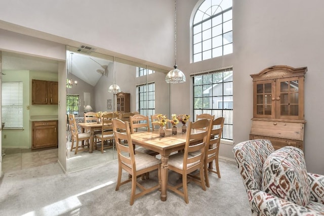 dining space with baseboards, visible vents, a high ceiling, light carpet, and a notable chandelier