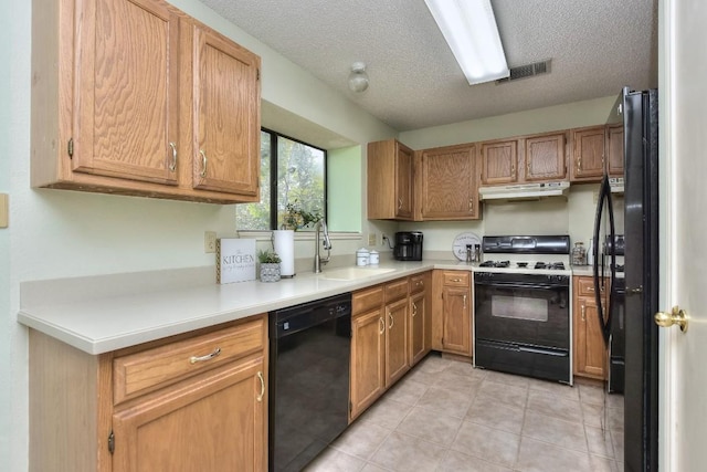 kitchen featuring visible vents, black appliances, under cabinet range hood, a sink, and light countertops