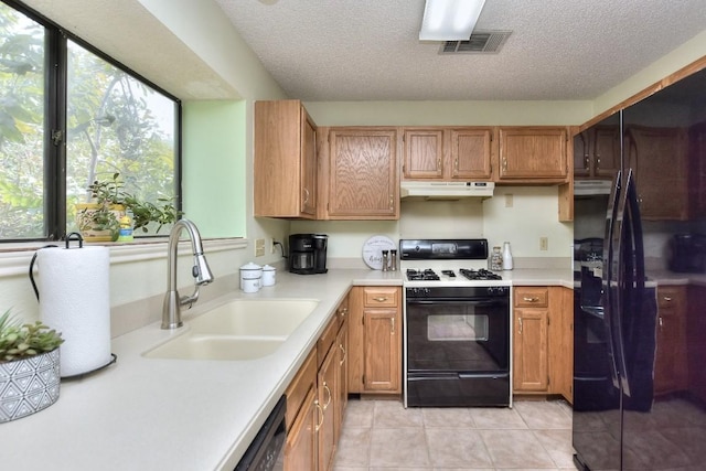 kitchen with visible vents, under cabinet range hood, a sink, gas stove, and light countertops