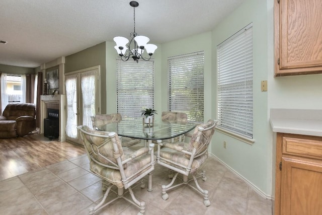 dining area featuring light tile patterned flooring, a notable chandelier, a textured ceiling, and baseboards