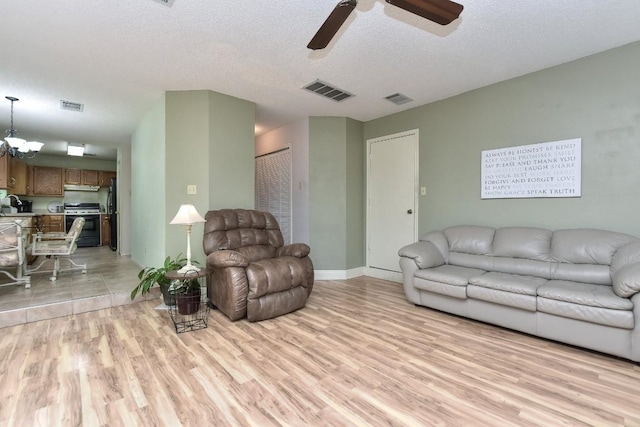 living area with visible vents, light wood-style floors, and a textured ceiling